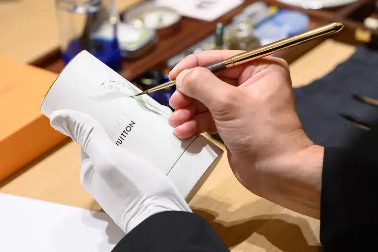 Photo réalisée dans le cadre d'un reportage métier par un photographe professionnel à Lyon. La photo représente les mains d'un photographe personnalisant un objet de la marque Louis Vuitton.