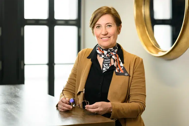 portrait corporate de Christine Reverchon-Masclet, fondatrice ASTERIS TALENTS, en veste camel et foulard graphique dans un bureau design avec verrière, photographe professionnel spécialisé en portraits de dirigeants